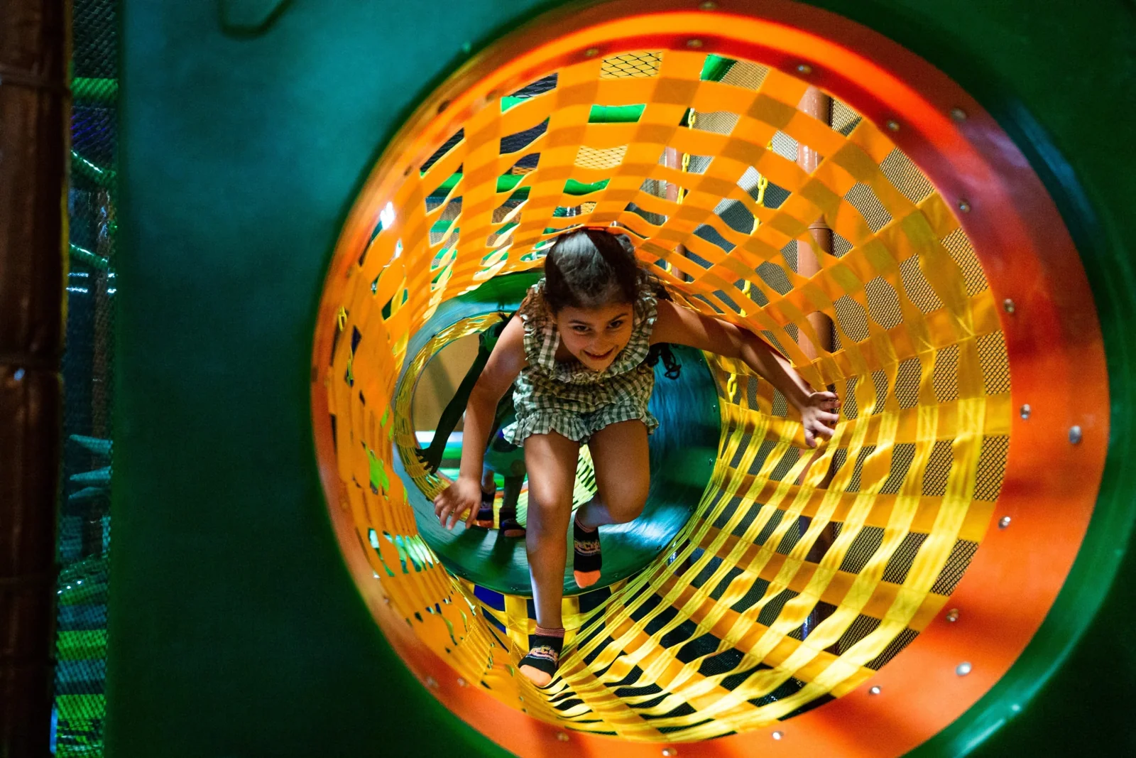 A child exploring a colorful padded tunnel at Recess